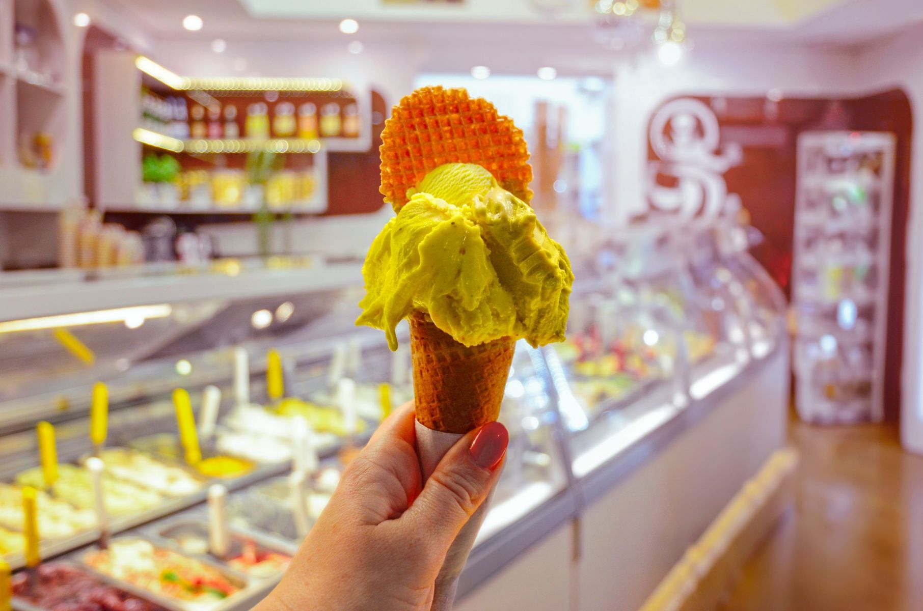 cream cone held in hand on the background of shop